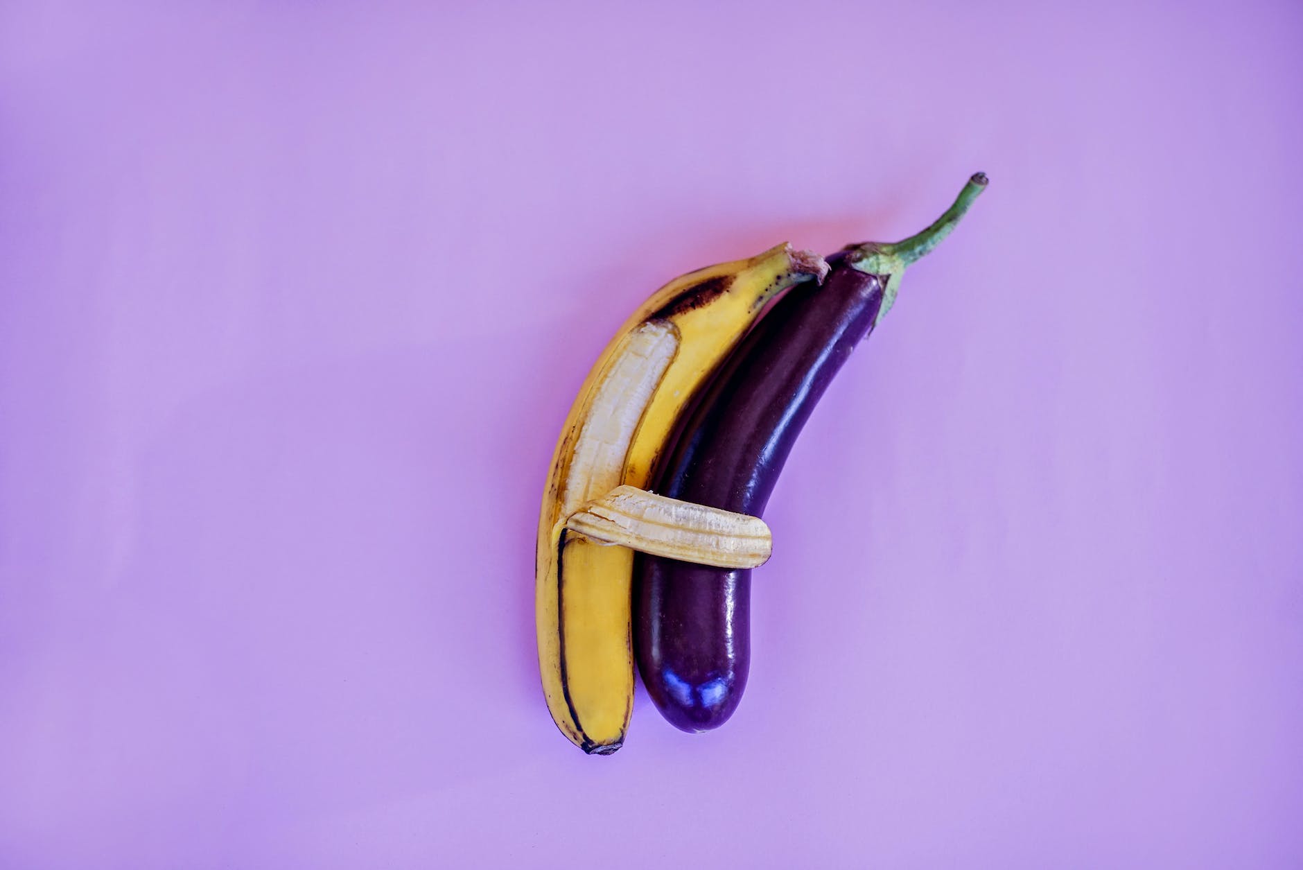 banana and eggplant on violet surface (sausage)