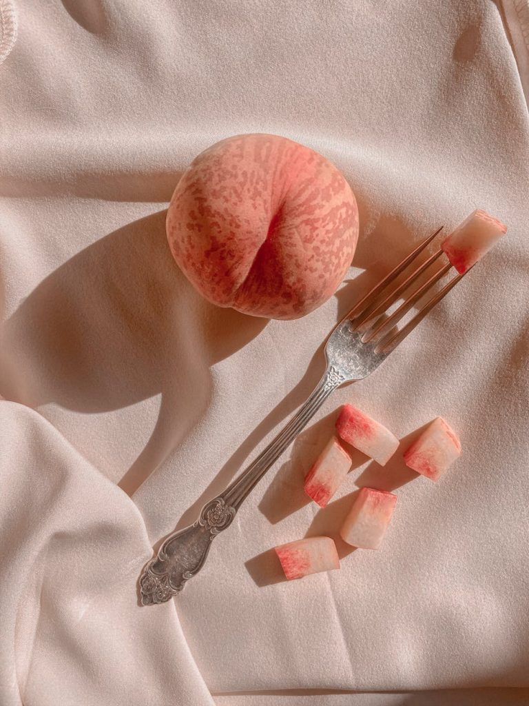 ripe peach with fork on draped fabric